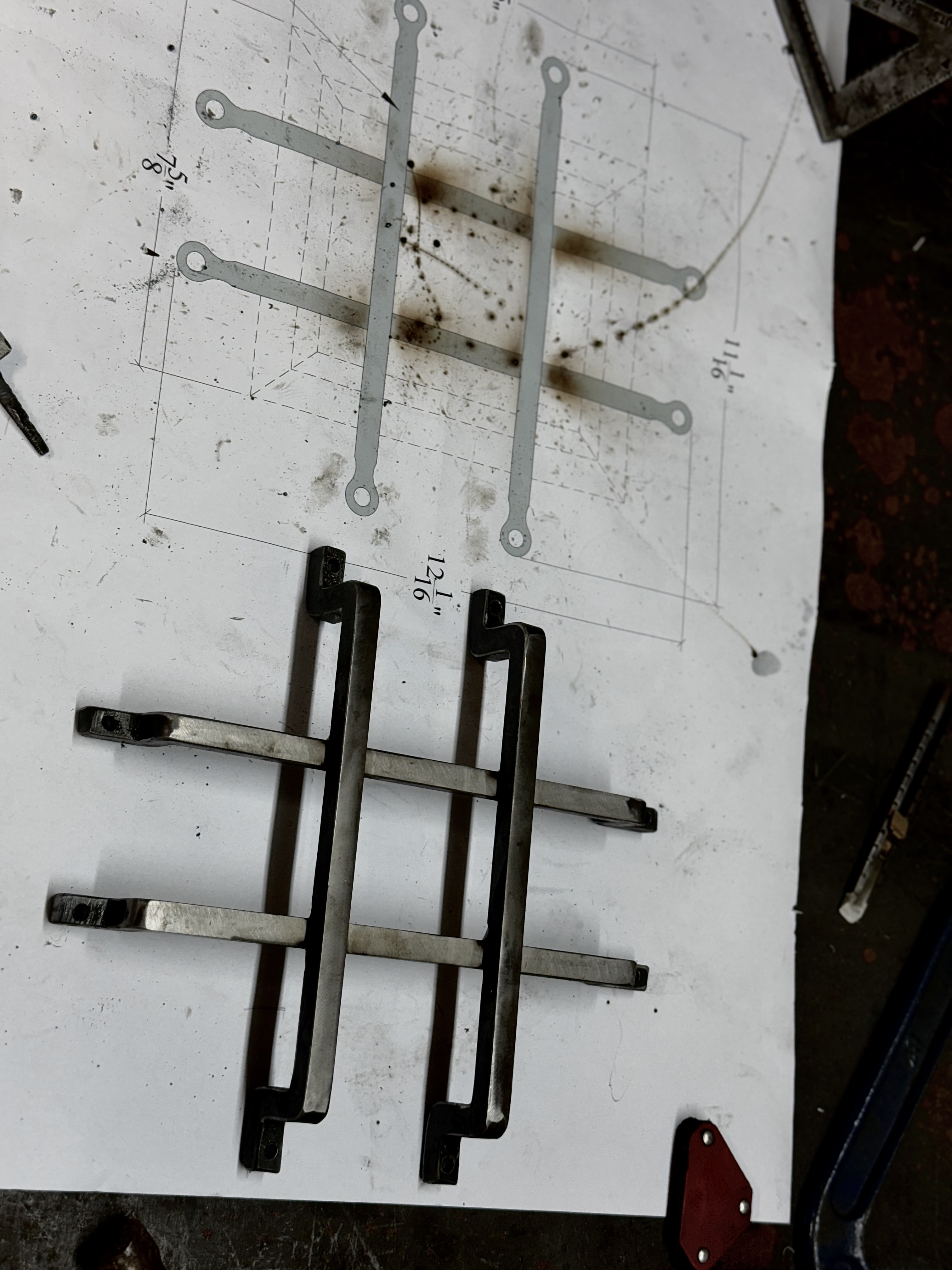 Custom metal parts laid out over a fabrication drawing